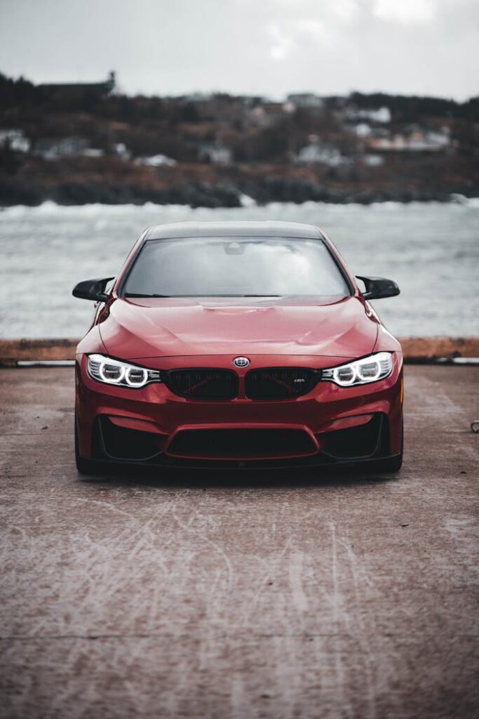 pexels-photo-9846134 Red sports car parked by the sea with a dramatic sky backdrop, perfect for automotive enthusiasts.